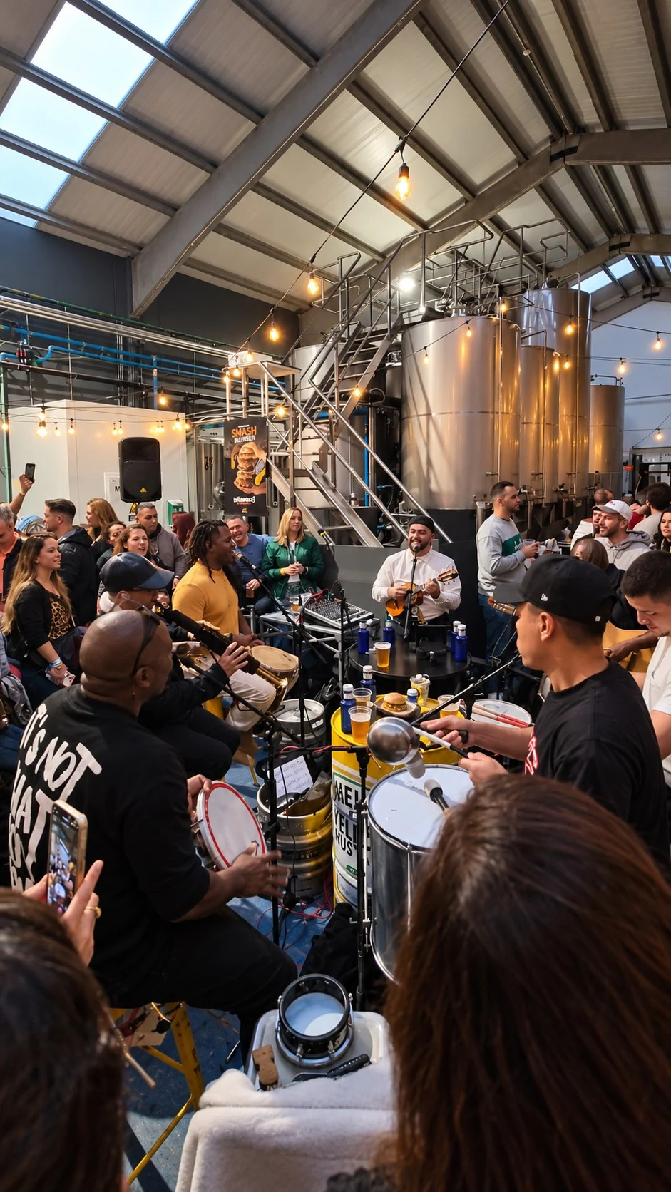 Música en vivo y público durante un evento entre los tanques de la nave cervecera