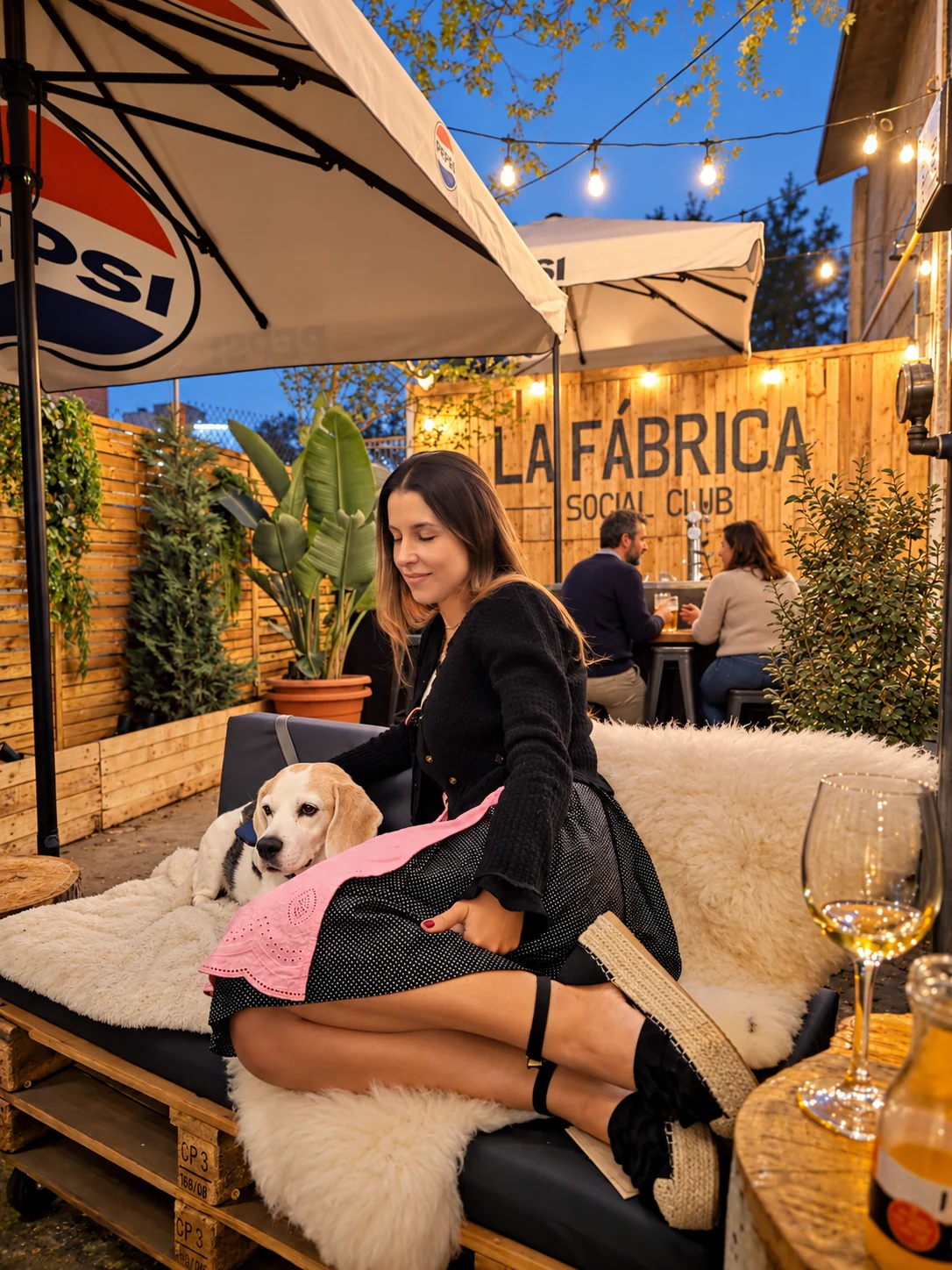 Una mujer con su perro en el lounge de La Fábrica, entre plantas, sofás y luces cálidas
