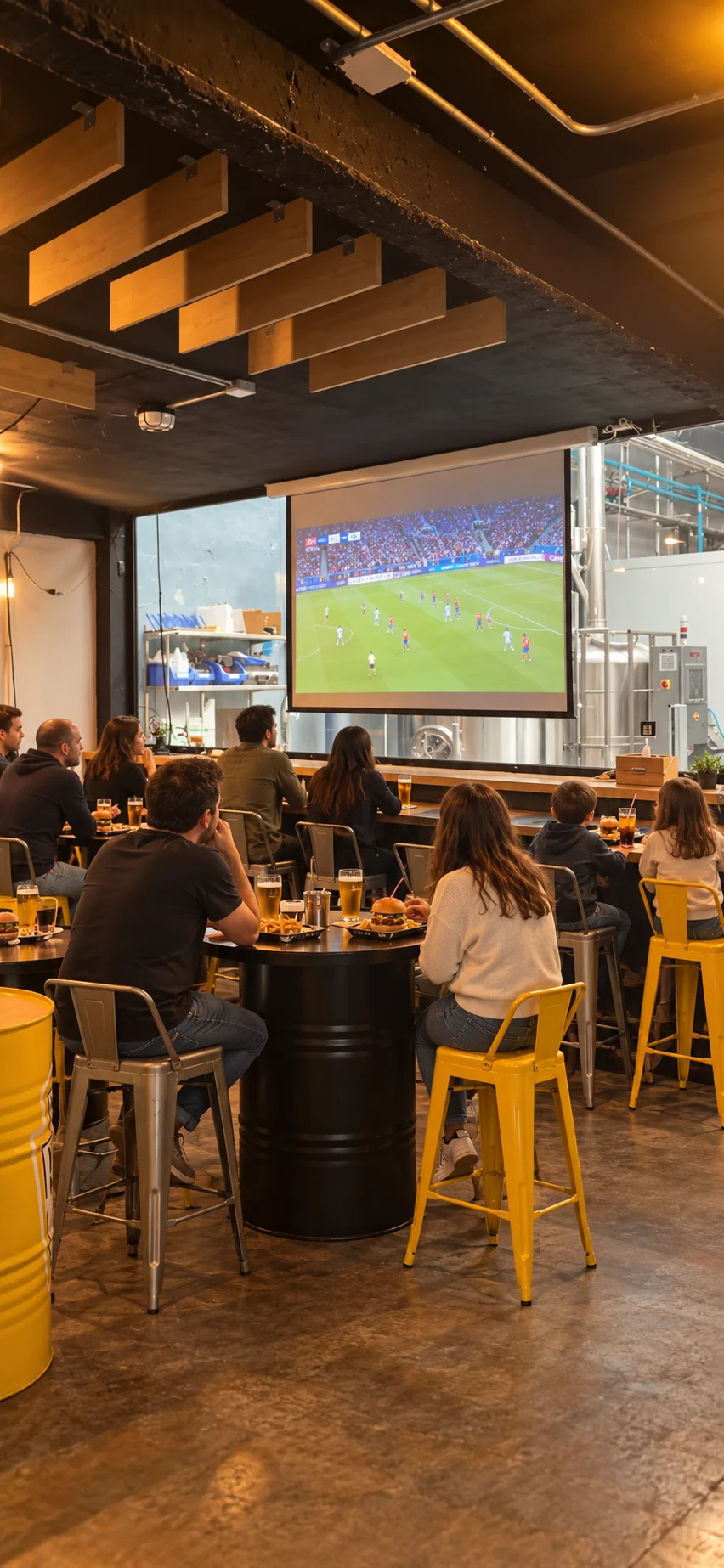 Zona de retransmisiones de La Fábrica junto a la cervecera, con partido en pantalla, burgers y cervezas